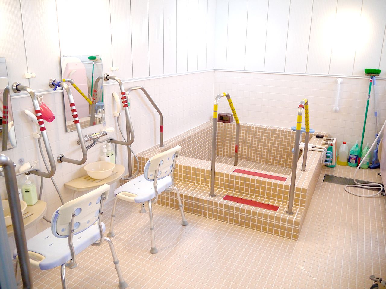 シャワーチェアが設置された浴室には大きな浴槽とたくさんの手すりが設置され、シャワーも付いている。