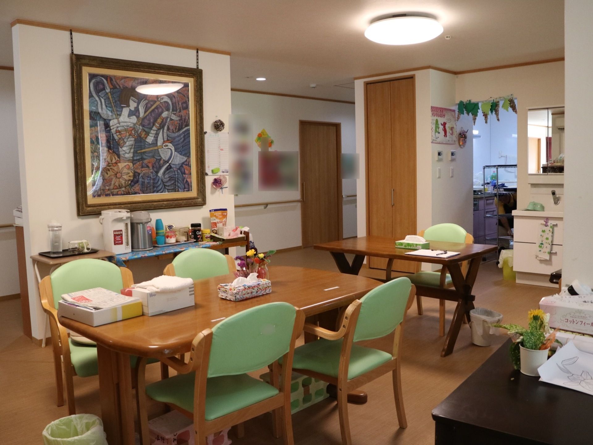 ダイニングテーブルと椅子が間隔を開けて２ヵ所設置されている。画面奥の壁には絵画が飾られ、その前にはポットや調味料などが並べられている。