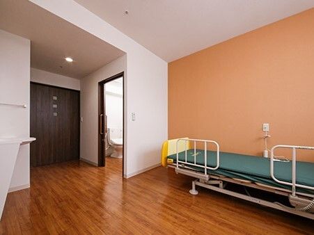 介護ベッドが置かれたフローリングの部屋にはトイレや車いす対応の洗面所も付き、家具などは置かれていない。