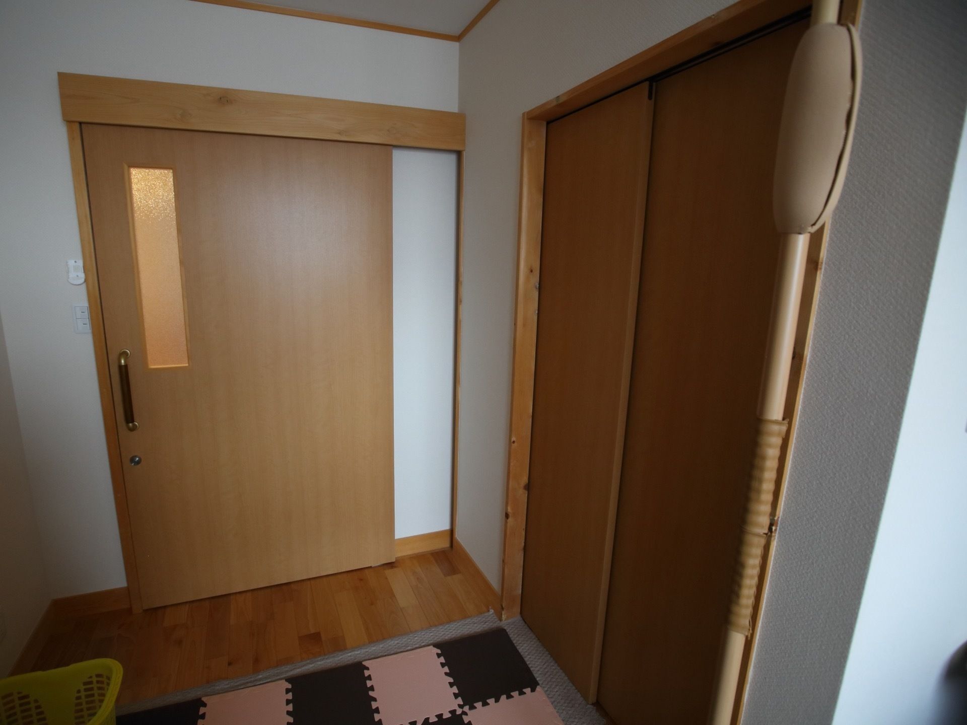 居室の出入り口の扉はスライドドアになっており、右にトイレが設けられている。床には、カーペットとジョイントマットが敷かれている。