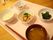 和食の献立である。みそ汁やご飯、おかずの小鉢が３つ、白いトレイの上に用意されている。箸も置かれている。