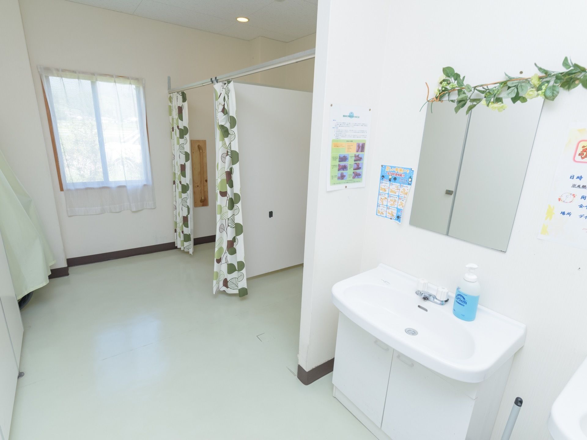 トイレに設置されている白い洗面台である。正面には鏡が設置され、下部には扉付きの収納が設けられている。