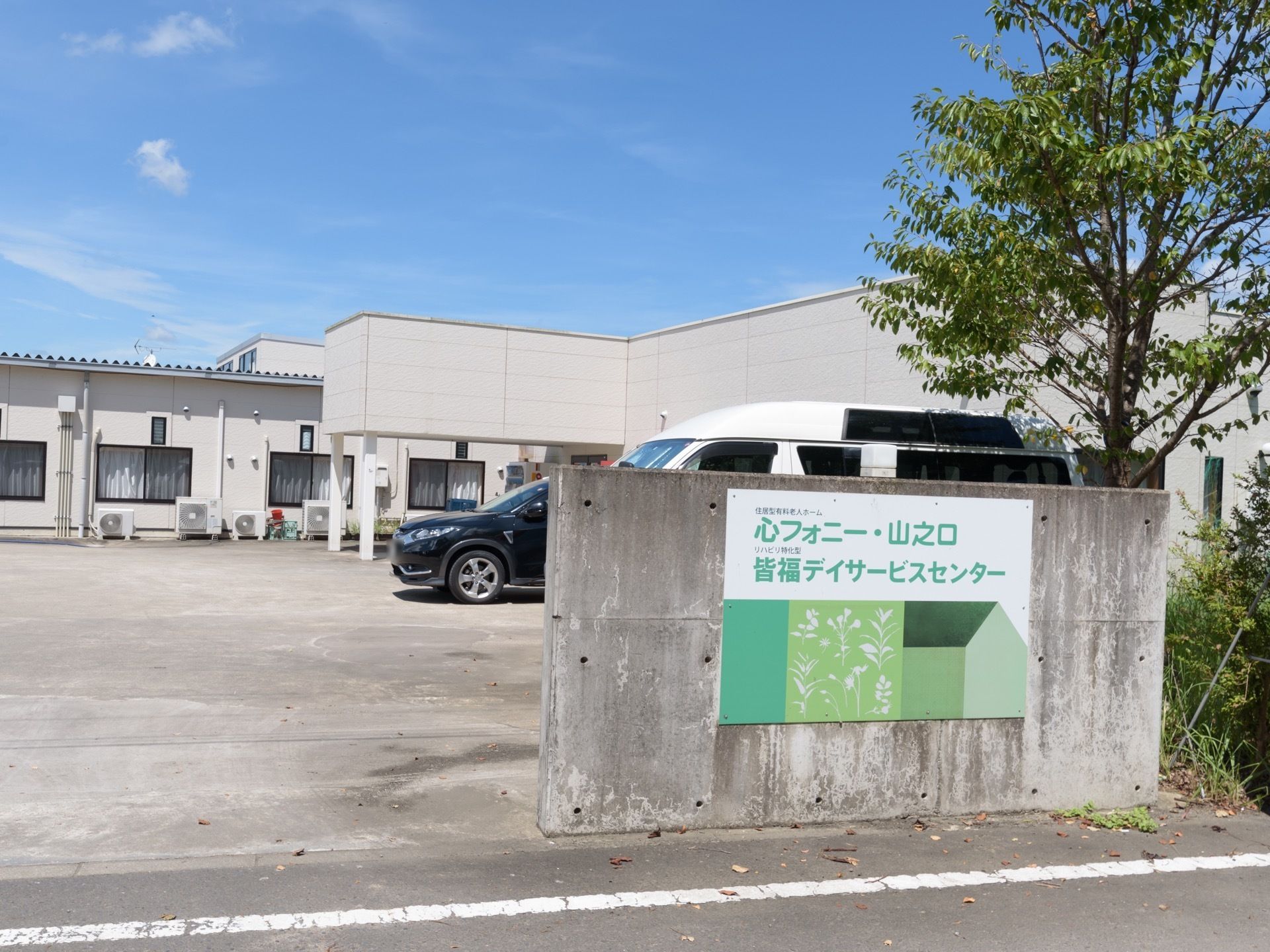 施設門壁のブロックに施設プレートがある。グリーン系をベースに施設名称と種別が明記されている。