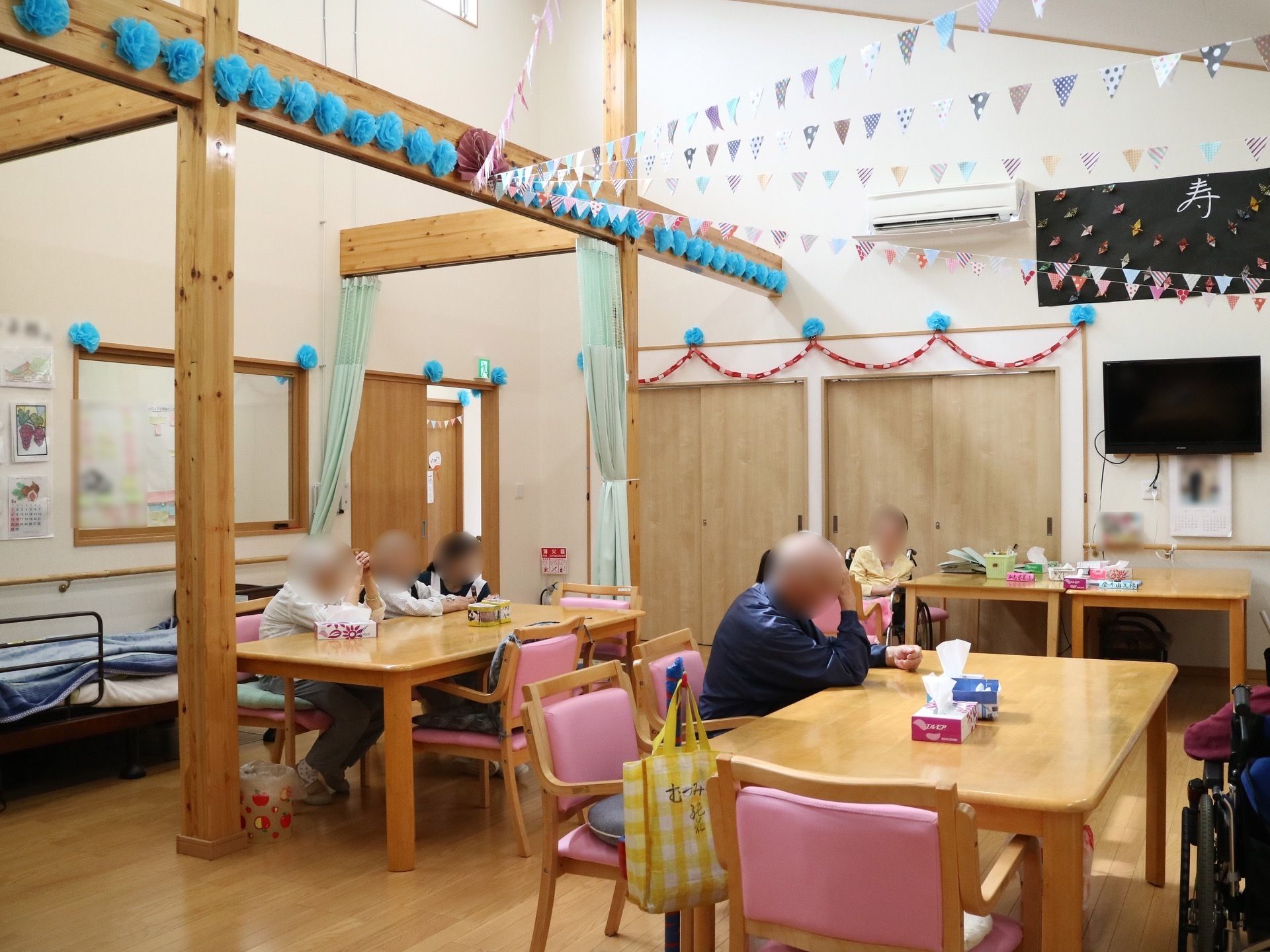 とても天井が高い共用の大部屋は、入居者様の憩いの場である。梁と壁との間には、ガーランドがかかっている。