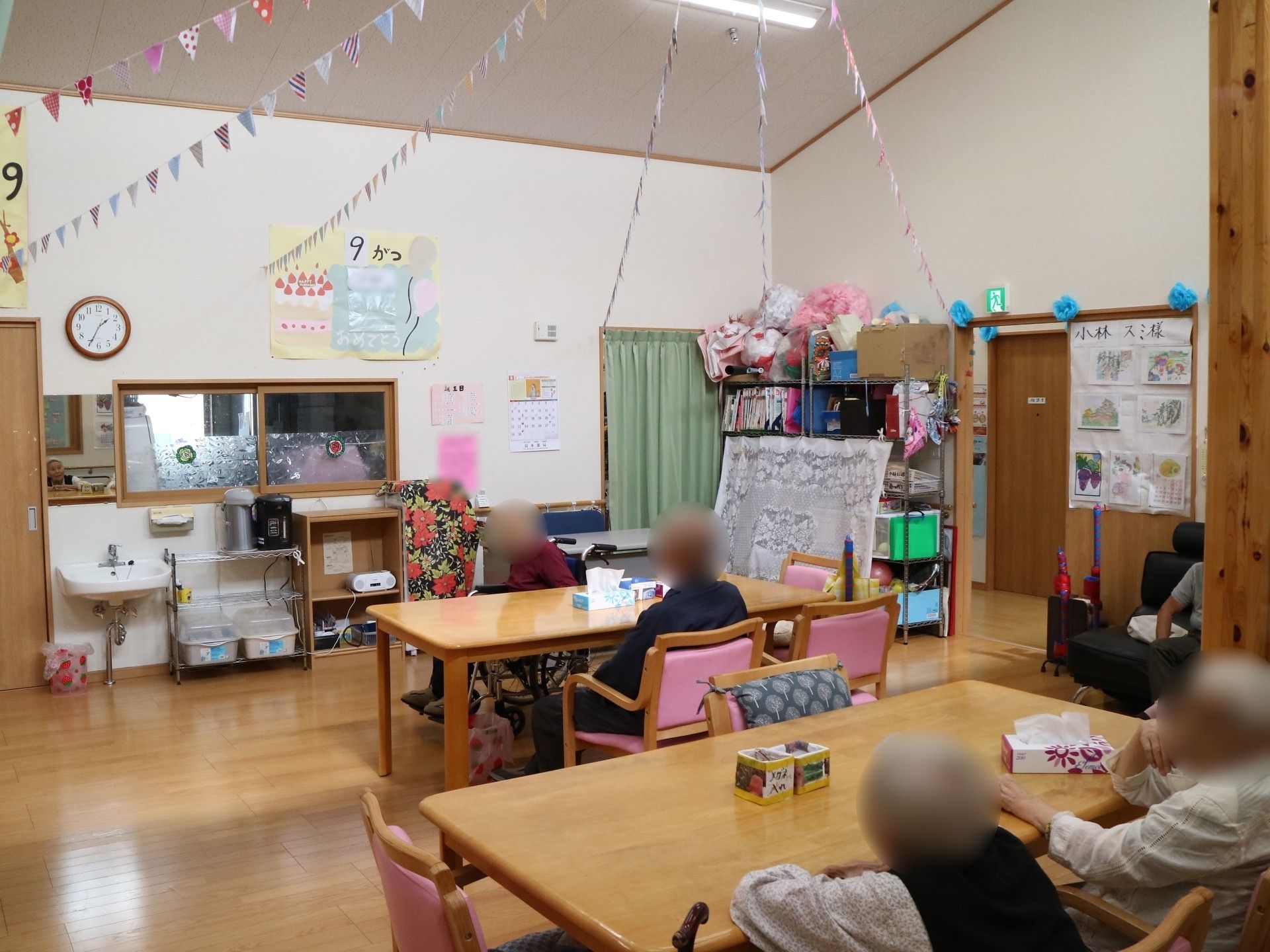 扉の枠には、花紙で作ったブルーの花をあしらっている。天井からは、淡いカラーのガーランドが壁にむかって伸びている。
