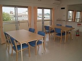 ブルーの椅子がセットされたダイニングテーブルが複数置かれているスペースにはベランダもある。
