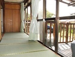 畳が敷かれた縁側は開放的な雰囲気。白いカーテンがまとめられていて、網戸などは付いていない。ウッドデッキのテラスにつながっている。