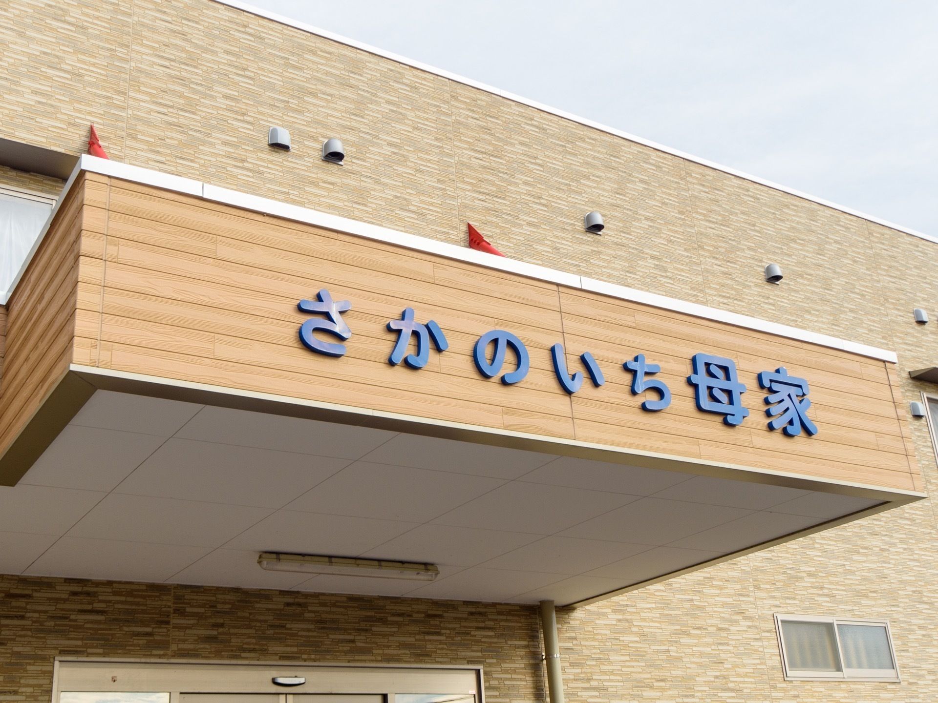 玄関前にひさしがあり、その幕板に青色の文字で施設名称が表示されている。ひさしの下には蛍光灯が一つついている。