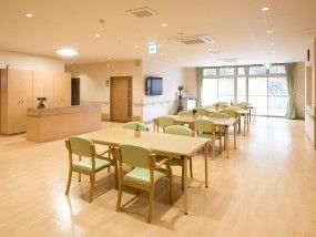 4人掛けのダイニングテーブルが複数置かれ、奥にはテレビがあり、窓も大きい。