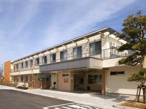 ２階建ての建物。２階にはベランダが付き、玄関には屋根がある。
