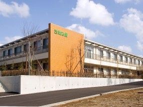 ２階建ての建物を道路側から見た様子。建物の周辺には垣根もある。
