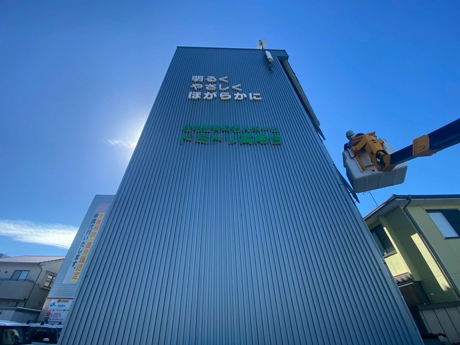 車いすの高齢女性と手を取り合って笑っているエプロンを付けた若い女性スタッフ。