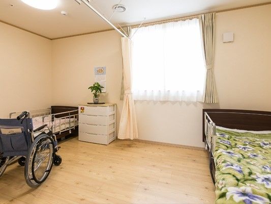 カーテンで仕切ることができる二人部屋。車いすやベッドが二台置かれている。