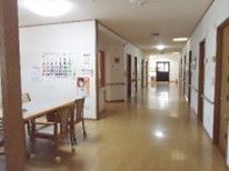 まっすぐに伸びた廊下。両サイドに居室ドアがあり、手前には共有スペースが設置されている。