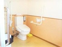 広いトイレ。コーナーに設置されたトイレには手すりが両サイドにつき、呼び出しボタンや手洗い場も設置されている。