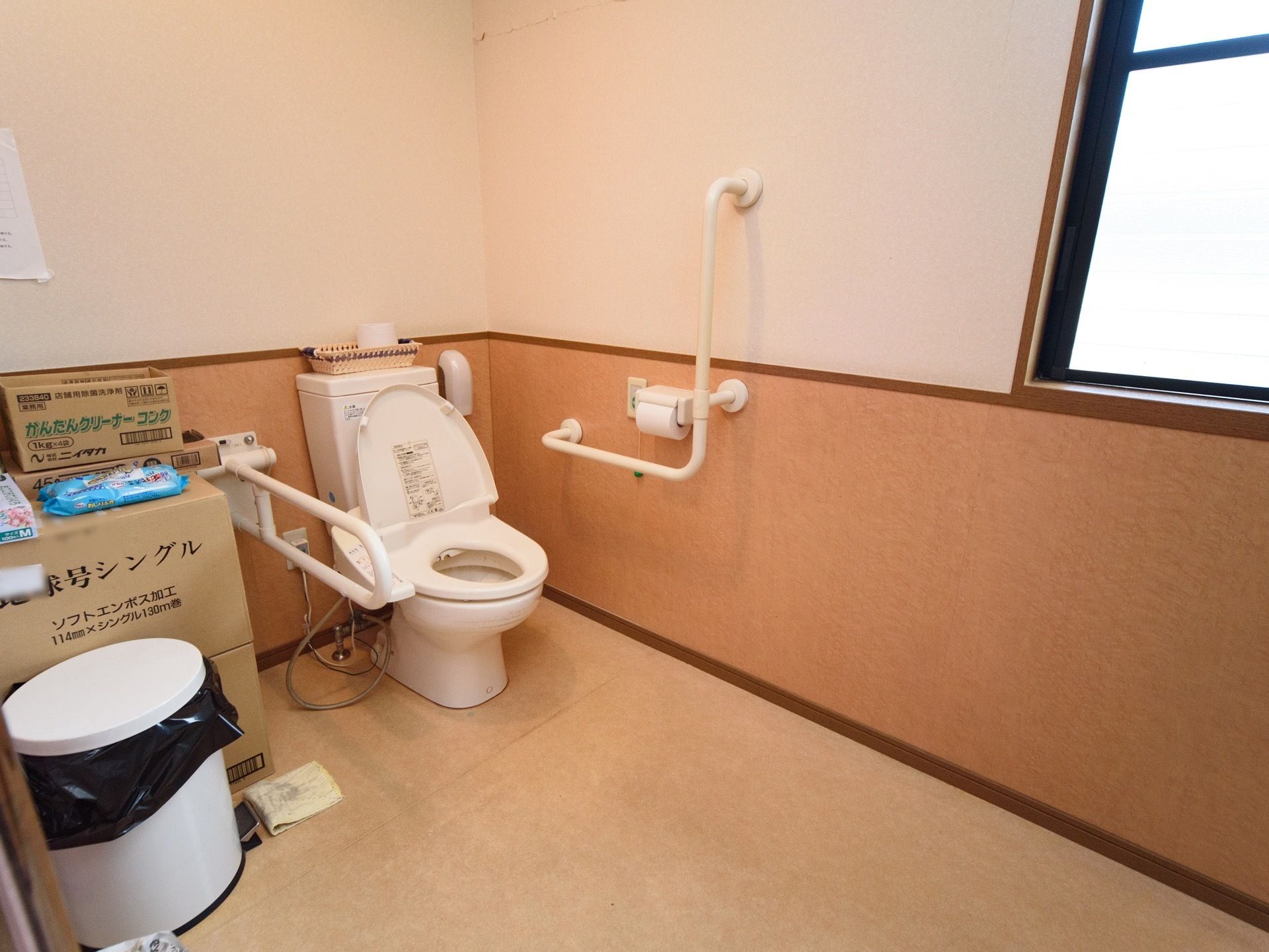 トイレの室内は広く、便座の横には掴まる場所がある。ペーパーホルダーの横に、緑色のボタンと緑色のボールが付いた紐が付いている。