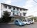 白色を基調とした、３階建ての施設である。グリーンの看板が外壁に貼られている。建物の前には、駐車場がある。