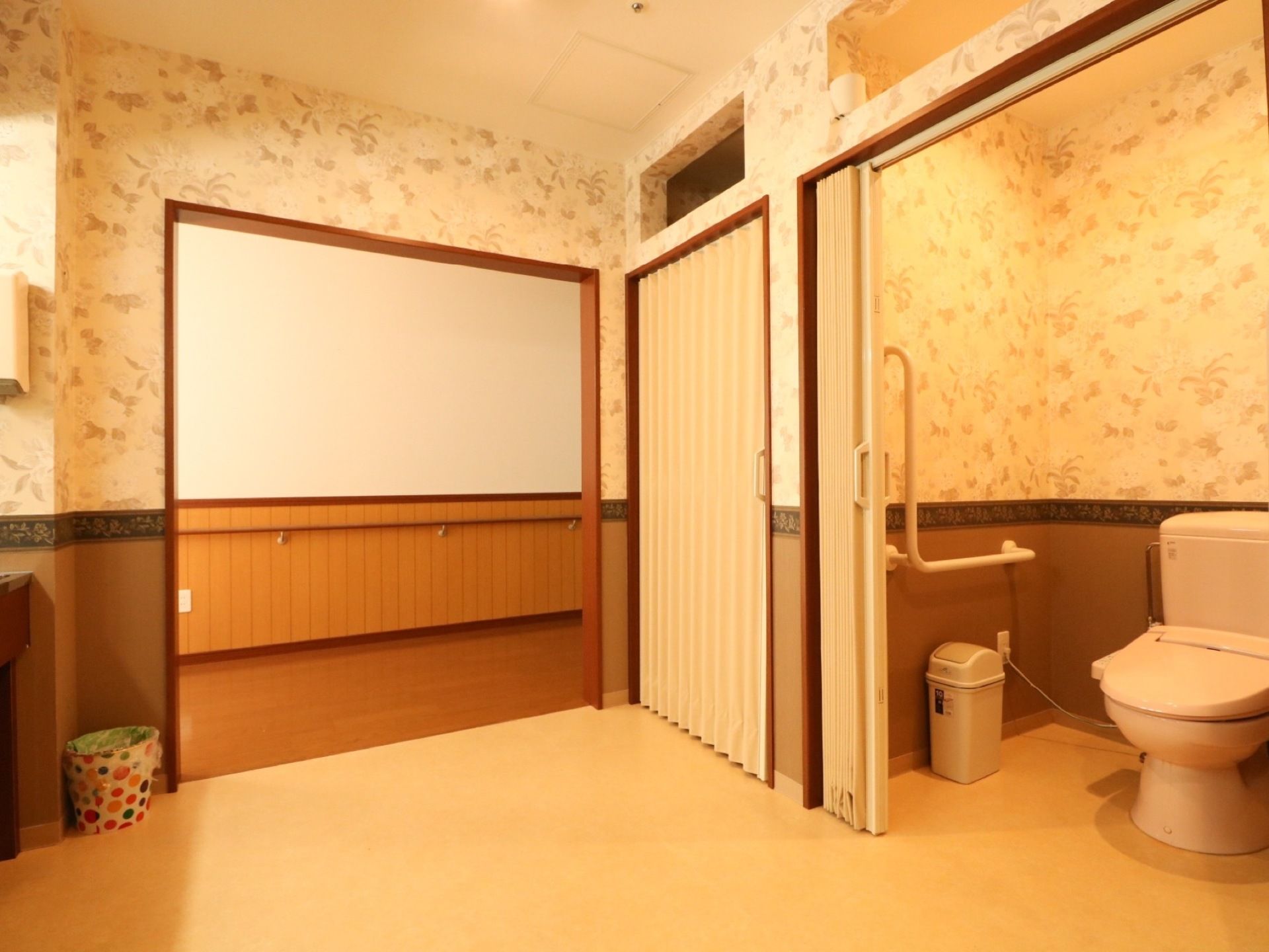 模様入りの壁を採用した、広々とした共同のトイレスペースである。一つ一つの出入口には、アコーディオンカーテンを取付けている。