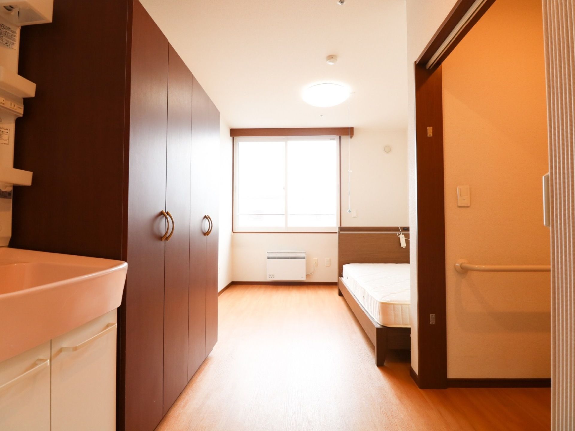 居室の床は木目調を採用している。壁際にベッドを配置し、洗面台、収納庫、トイレを備え、快適な生活空間を整えている。