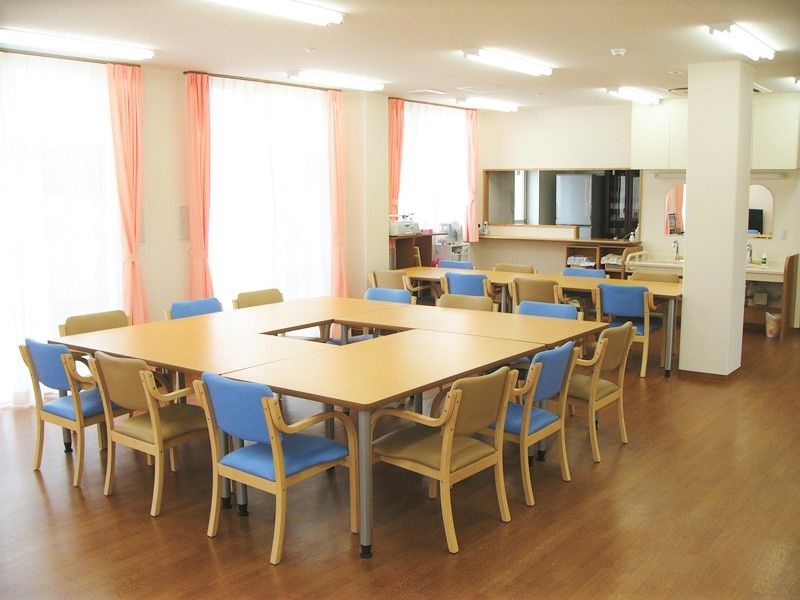 食堂には複数のテーブルが置かれ、大きな窓があり明るい雰囲気。奥にはキッチンもある。