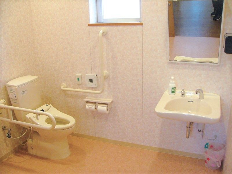トイレはフローリングで白い壁。車いすでもゆとりがある広さで、手洗い場もついている。