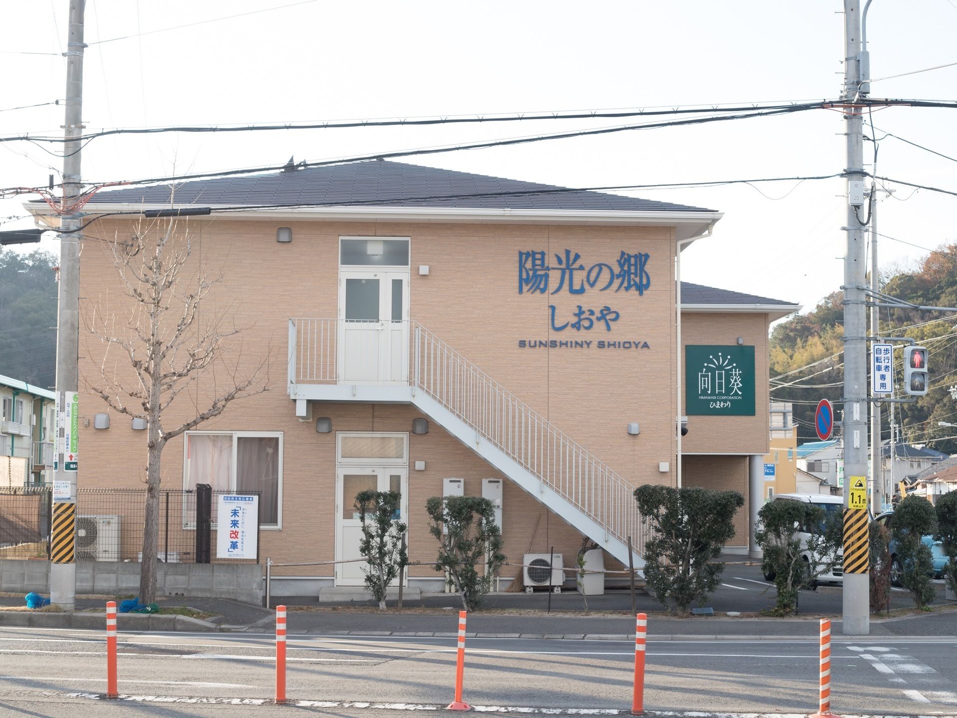 大通りに面しており、車道と施設の間には歩道が整備されている。歩道側には、フェンスや樹木で区切られている。