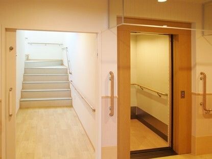 右側にはエレベーター、左側には階段があり、どちらにも手すりが付いている。階段は日当たりもよい。