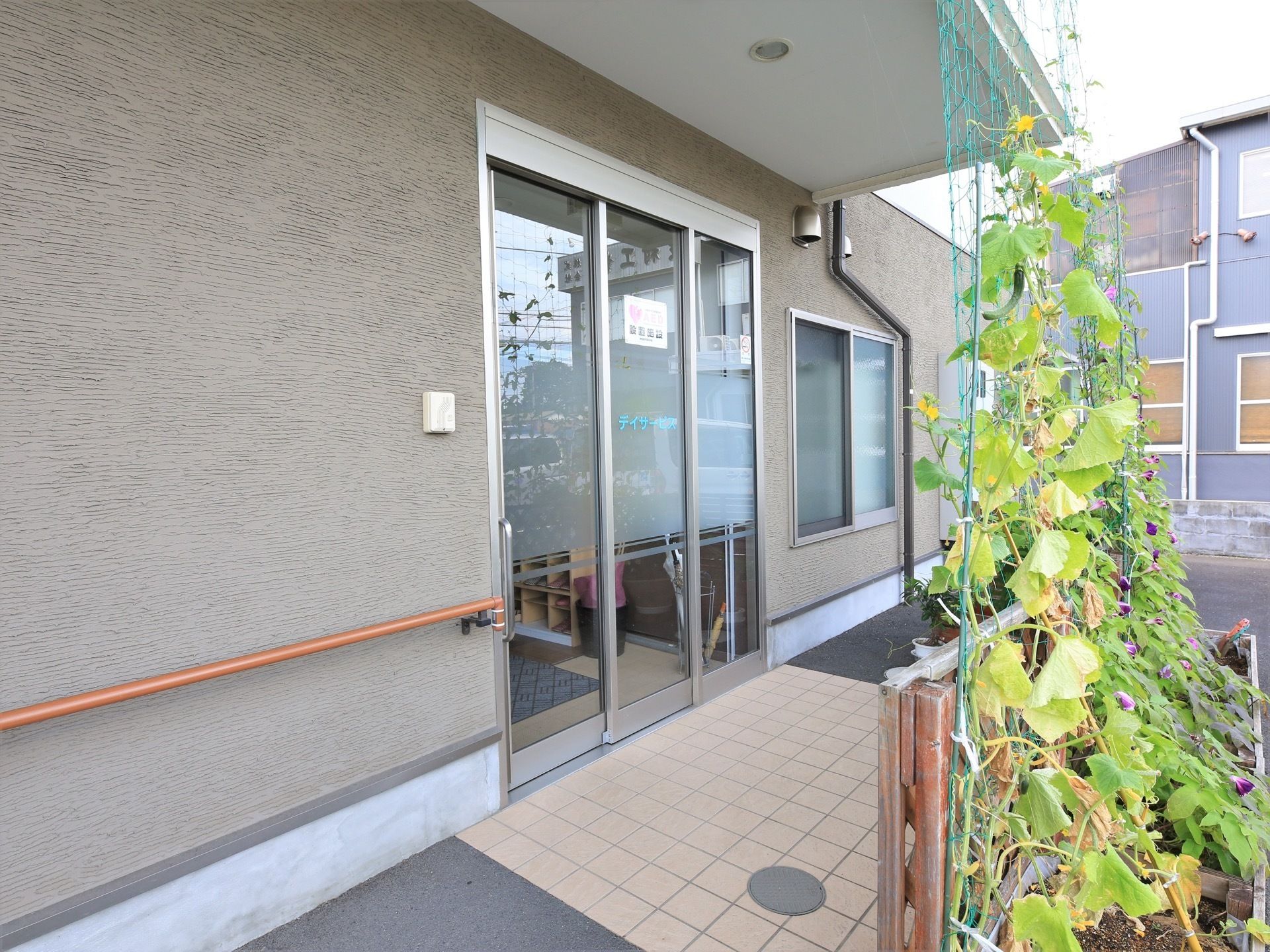 玄関には屋根があり段差がなく広々とした空間である。軒先ではきゅうりが育てられており、グリーンカーテンになっている。