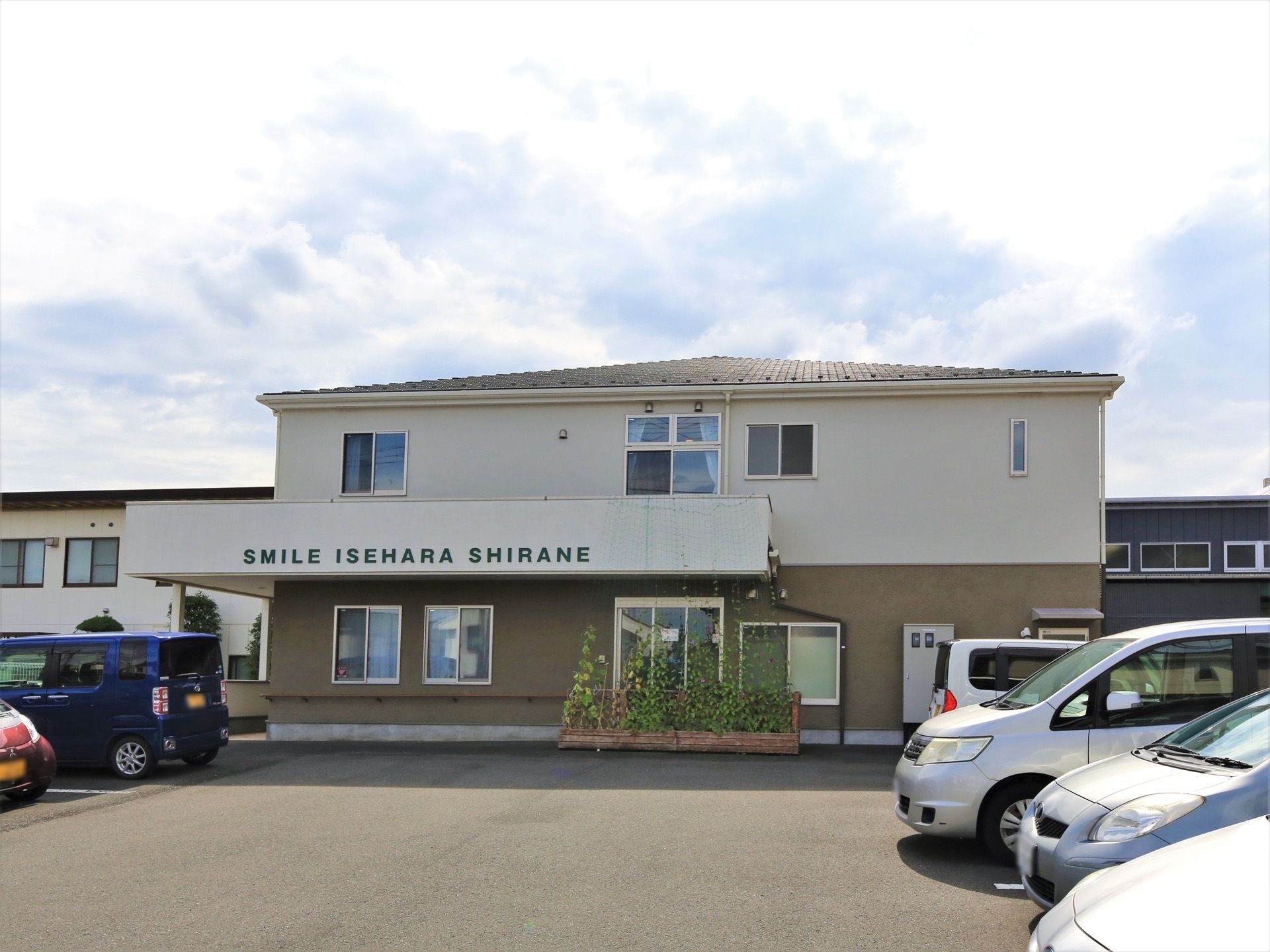 建物は２階建てで、白とベージュのツートンカラーである。広い駐車場が完備されている。日当たり良好である。