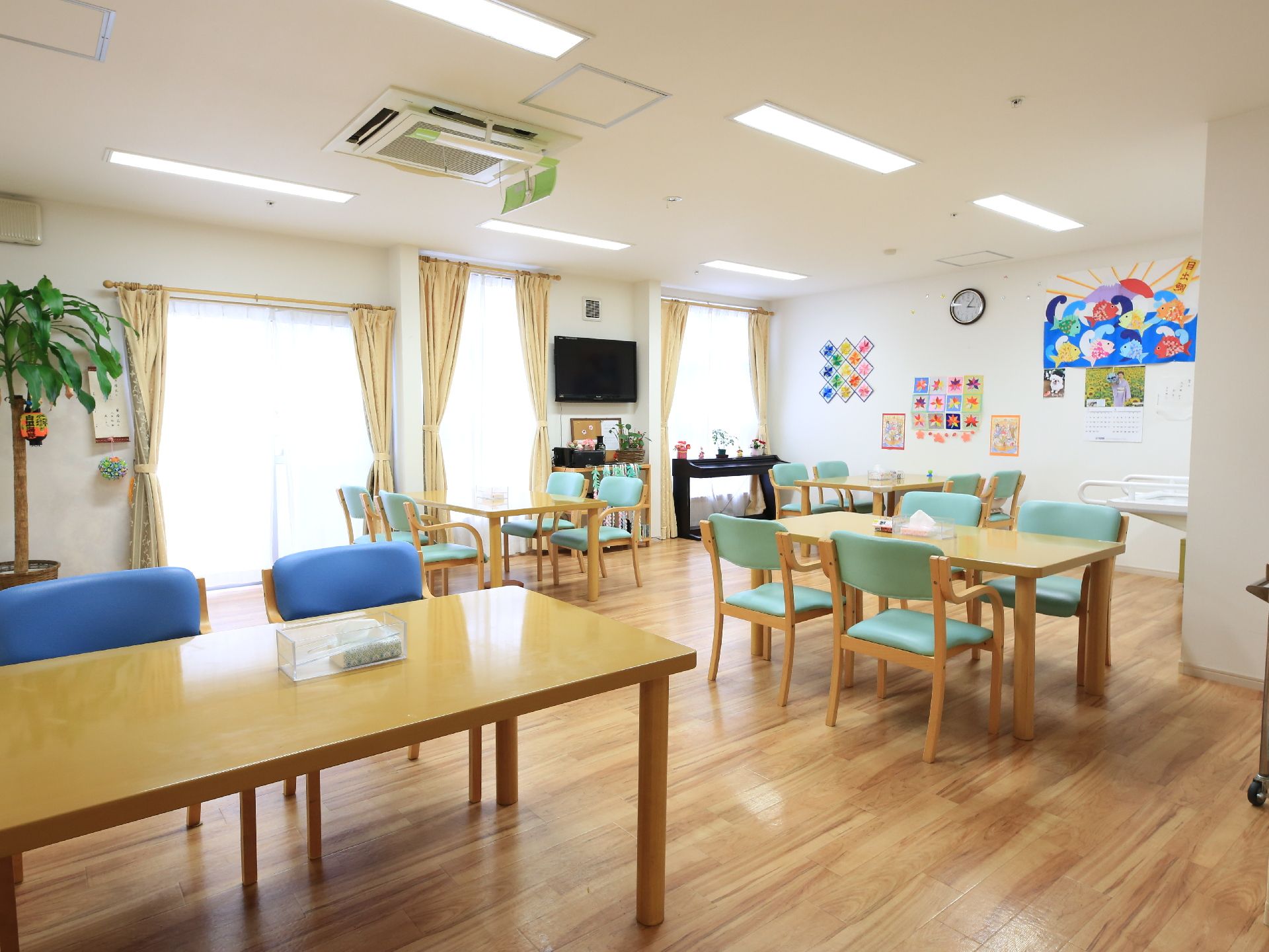 座り心地のいい椅子が並べられた机とテレビ、ピアノがある部屋