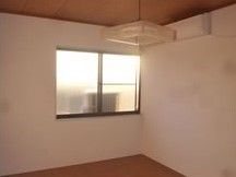 居室はシンプルで家具などは置かれていない。白い壁に窓が一つ、和風の照明器具が付いている。