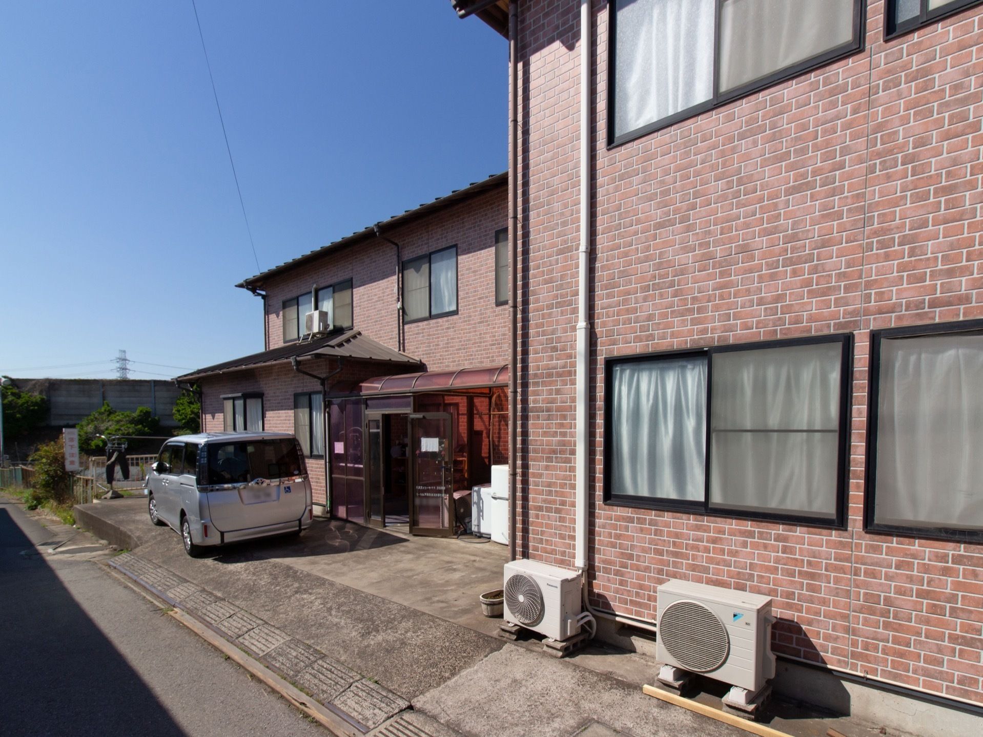 施設の周りには高い建物がなく、ゆったりとお過ごしいただける環境である。施設の外壁はダークブラウン色になっている。