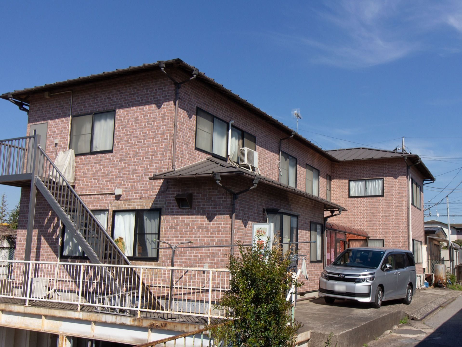 外壁はブラウン色で２階建ての建物である。外階段が設置されており、いざという時に２階から直接避難することができる。
