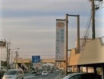 車が通る道路の横に「ほのぼのデイサービス」と書かれた看板がかかっている。