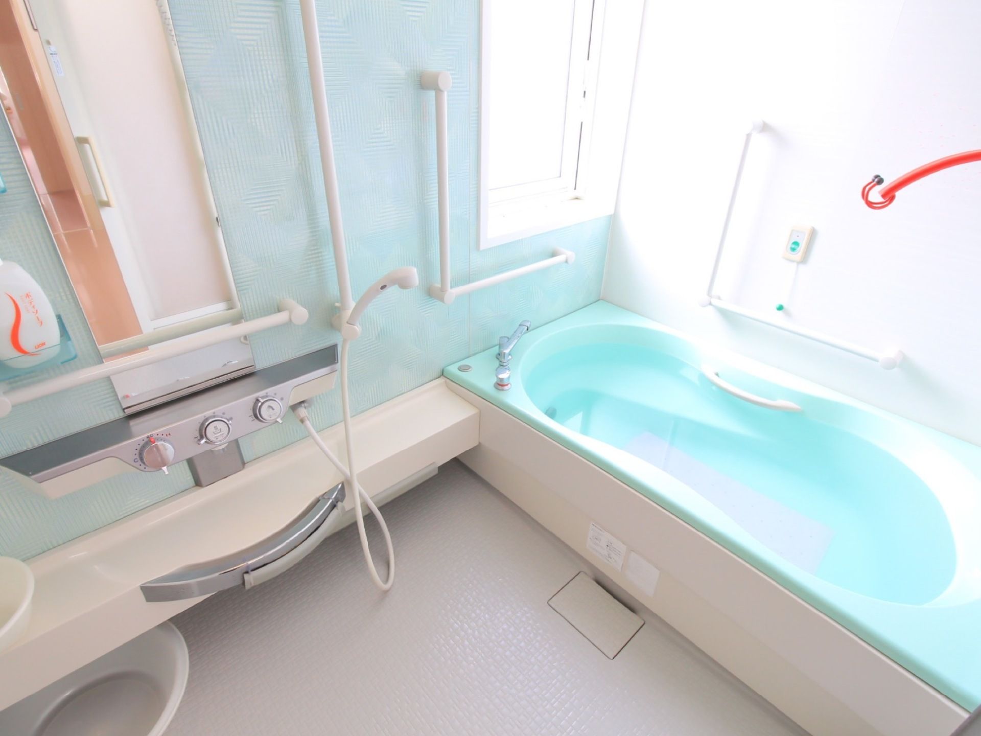 浴室内の白い内装に、アクセントでパステルカラーが使われている。浴槽も明るい色合いにして、オシャレな印象。