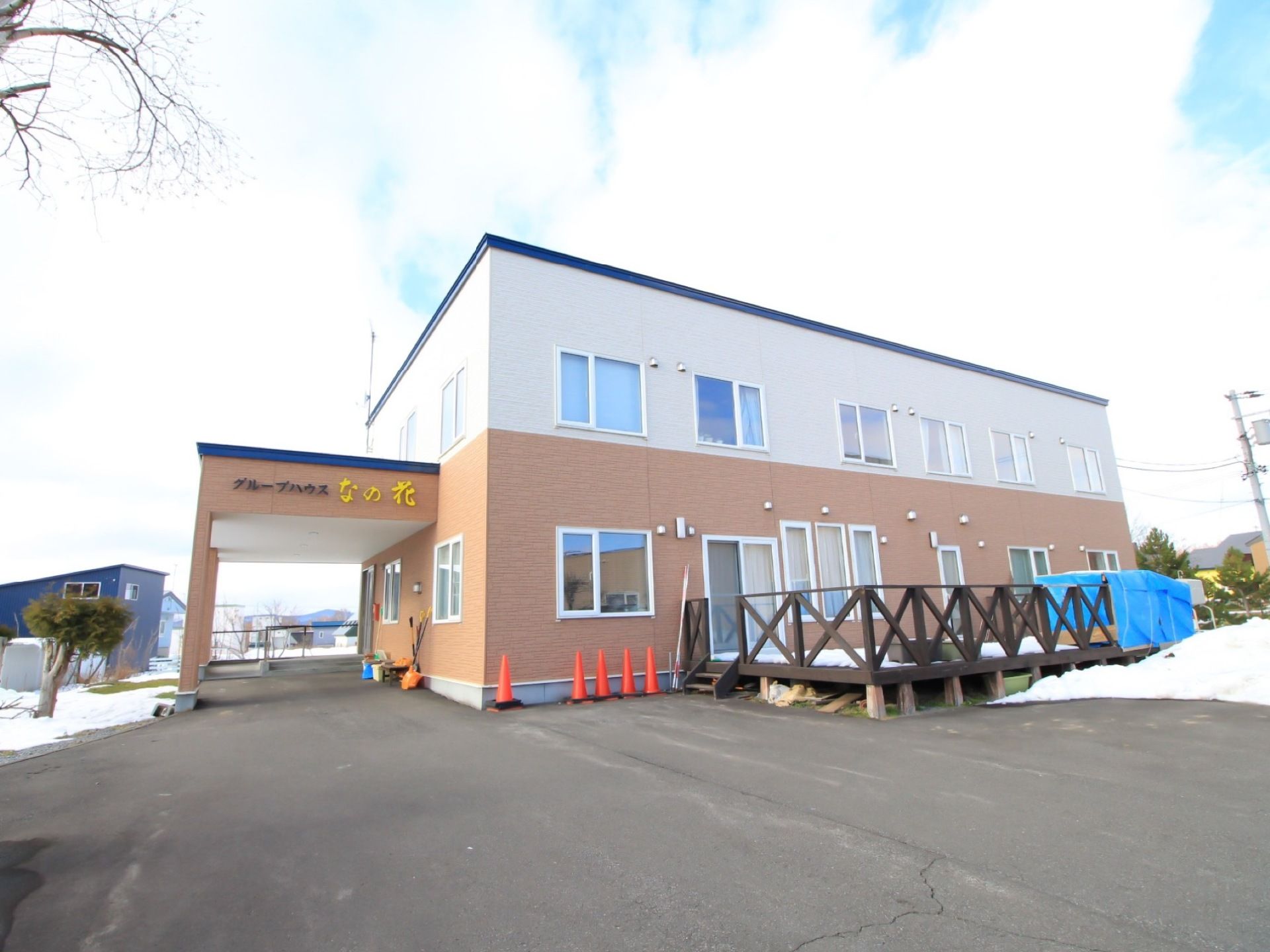 白とベージュのツートンカラーが個性的な外装の建物。ウッドデッキが設けられていて、オシャレな印象になっている。