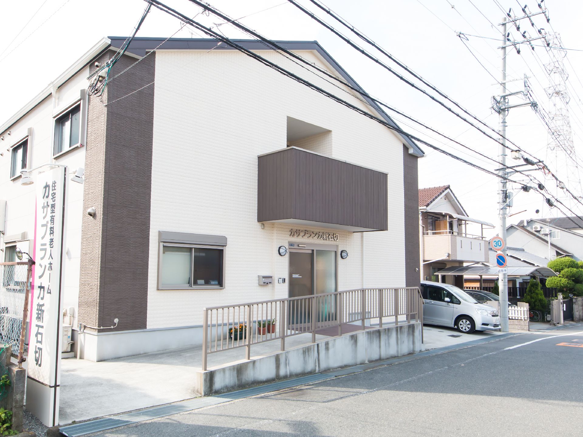 入口がスロープになった、二階建て住宅型の老人ホームの外観