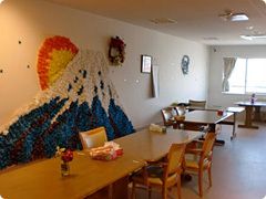紙で作られた富士山の壁画が飾られた食堂には大小のダイニングテーブルが複数置かれ、テーブルの上に花も飾られている。