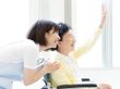 なにかに笑顔で手を振っている女性とその人の方を持ち同じ方向に笑顔を見せているスタッフ