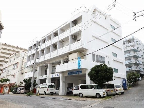 鉄骨造4階建ての建物の様子。駐車場スペースがある広めの敷地内