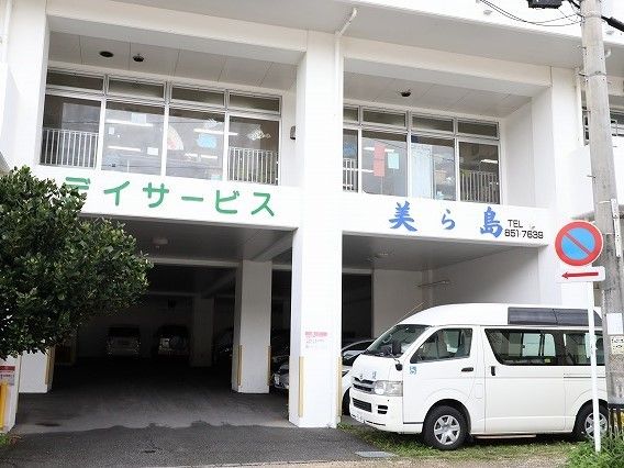 鉄骨造４階建ての建物の様子。駐車場スペースがある広めの敷地内