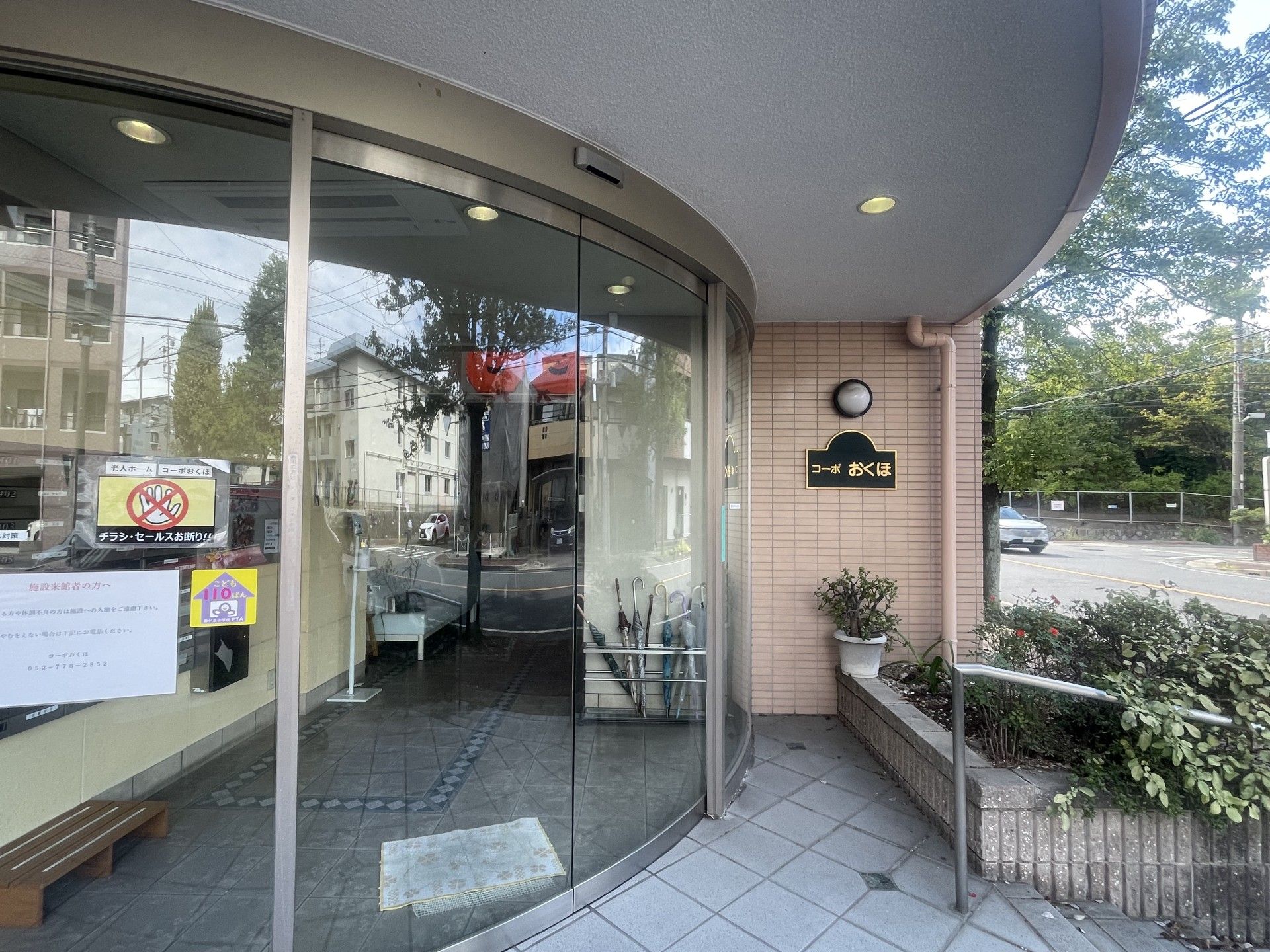 エプロンを付けた若い女性スタッフがブラウスを着た高齢女性と笑顔で話している。スタッフはカルテのようなものを持っている。