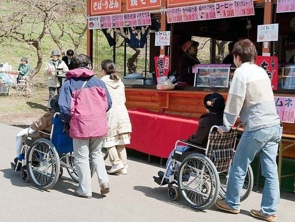 車いすの高齢者が外出している様子。施設スタッフが車いすを押している