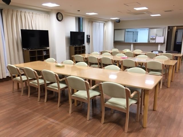 厨房がすぐそばにある食堂には大きなダイニングテーブル３組あり、大きなテレビも2つ置かれている。
