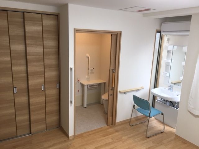 クローゼットの隣には手すりが付いた広いトイレがあり、大きな鏡が付いた洗面所には椅子がセットされている。