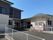 幅の広いアプローチが付いていて、右側には平屋建ての建物、左側には2階建ての建物があり、自動販売機もある。