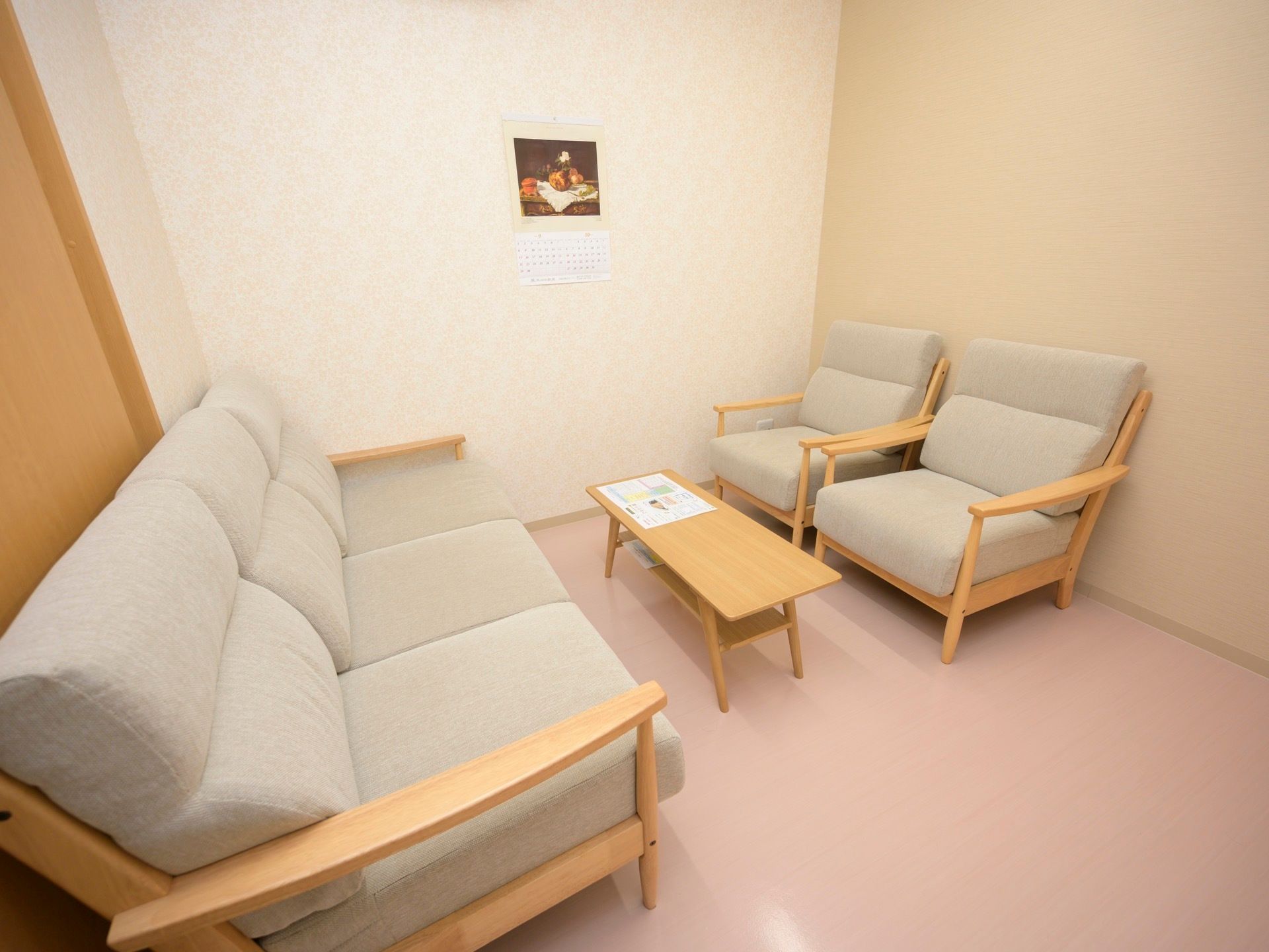 落ち着いた色調の談話室がある。３人掛けのソファと、１人掛けのソファが２脚置かれている。壁には小さな絵画が飾られている。