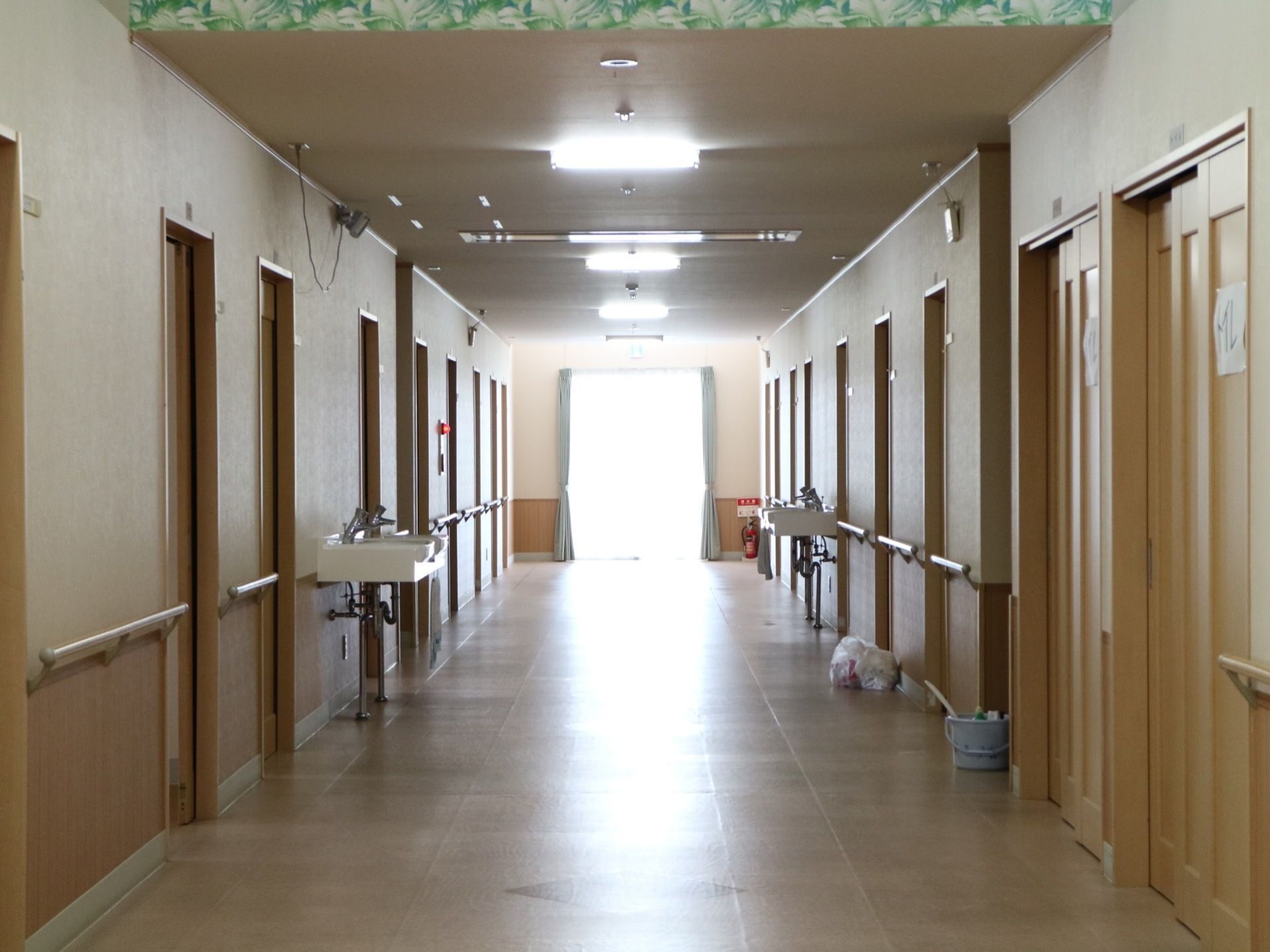 居室が立ち並ぶ廊下で、途中には洗面台がある。突き当たりには大きい窓があり、隅に消火器を用意。