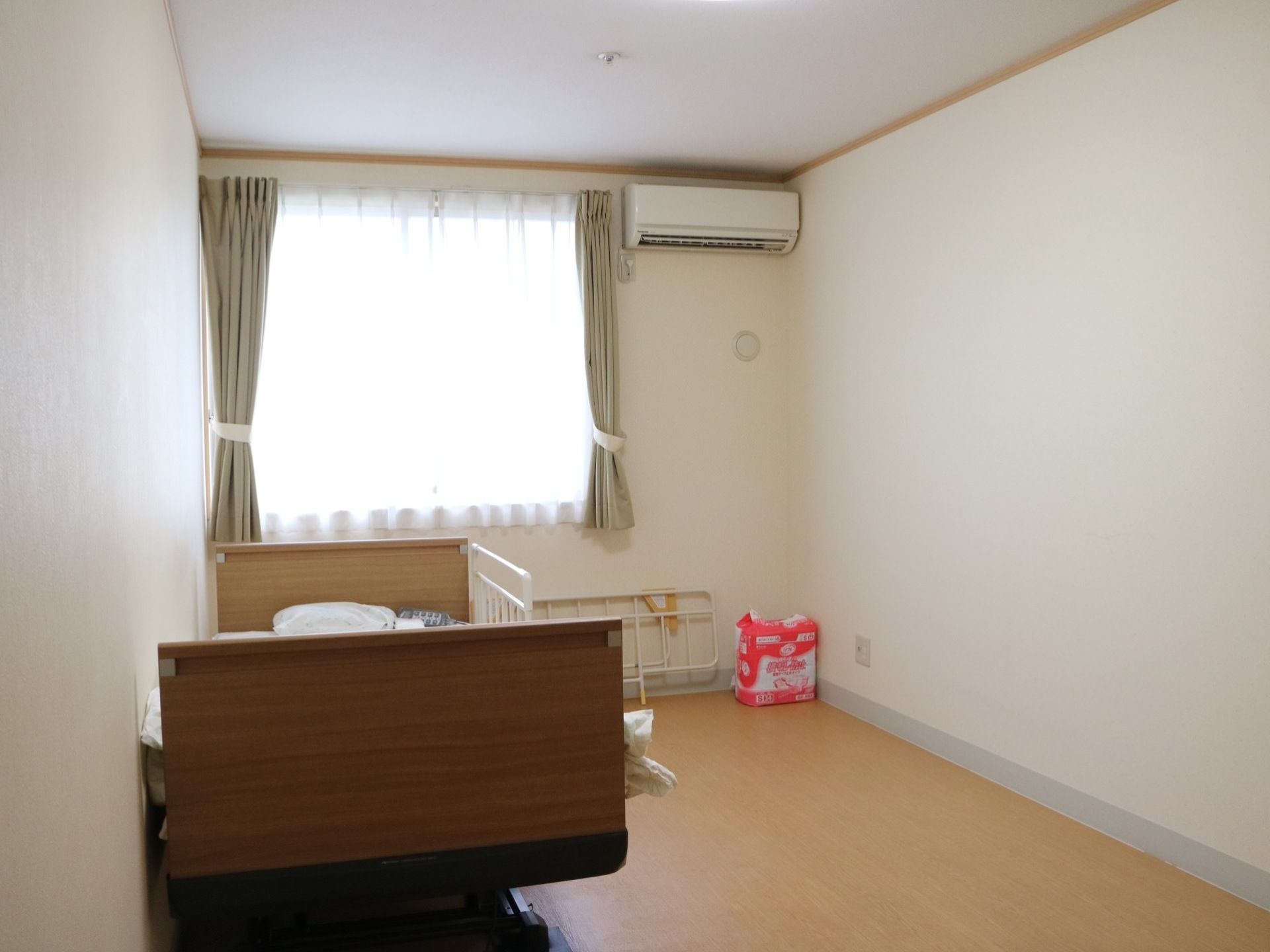 明るい居室で、ベッドの右側には余裕のある移動空間を確保している。入居者様はゆったりと通行することが可能。