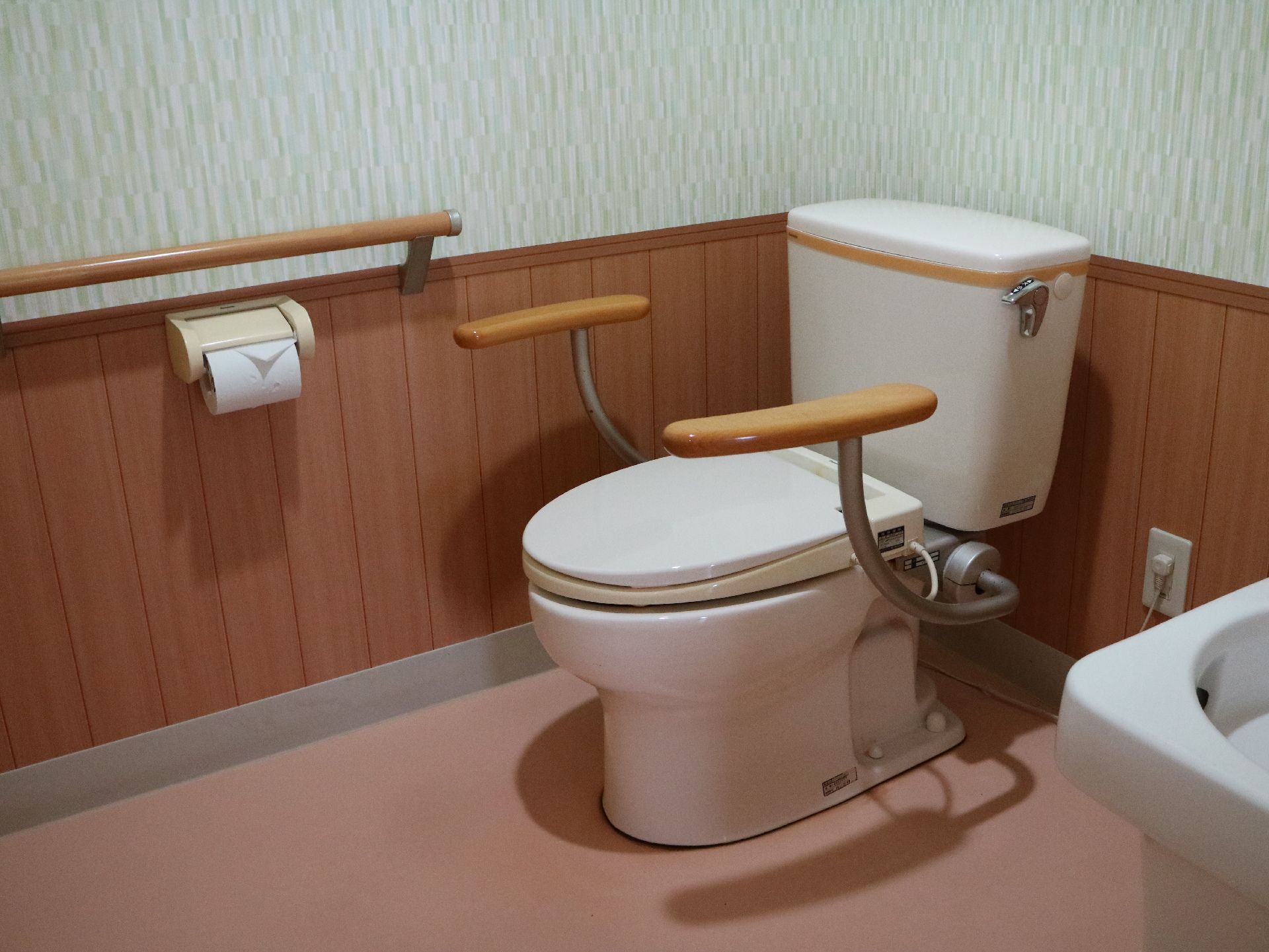 両サイドに手すりがつけられた洋式便器があるお手洗い